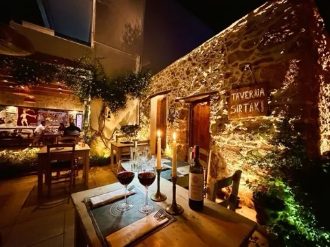 Stone-walled garden of Sirtaki Tavern lit at night